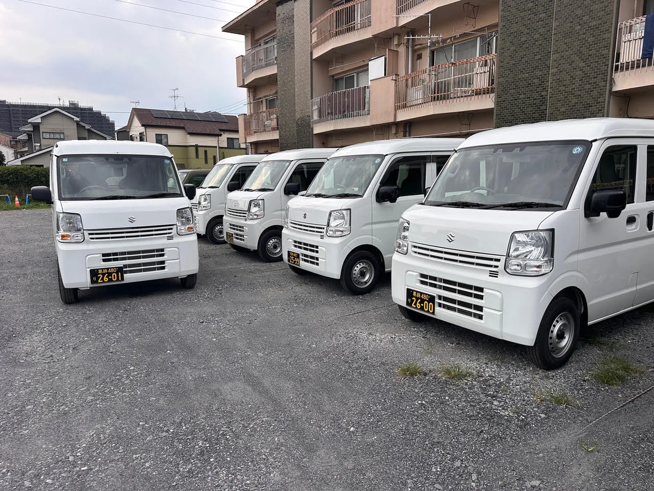 駐車場に並ぶ軽貨物車両